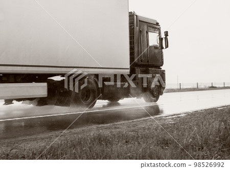 A truck with a semi-trailer transports cargo in bad rainy weather with insufficient visibility. Black and white photography. Road traffic accident. Copy space for text 98526992