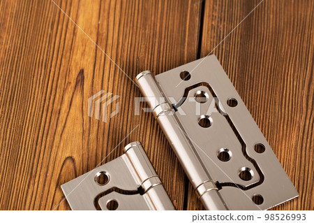 door metal hinges on a wooden background, macro. Door furniture 98526993