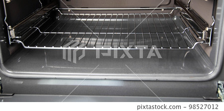 Modern electric oven with a grate on telescopic rails. Close-up Modern electric oven with a grate on telescopic rails. Close-up 98527012