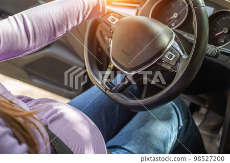 A pregnant woman wearing a seat belt drives a car. Safety and driving during pregnancy. 98527200
