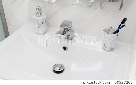 Modern and clean washbasin with pop-up waste. Washbasin interior with liquid soap and toothbrushes. Modern and clean washbasin with pop-up waste. Washbasin interior with liquid soap and toothbrushes. 98527205