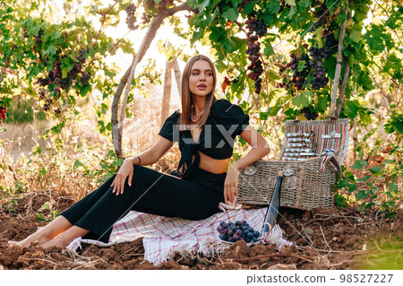 Young blonde woman sitting on a picnic in a vineyard 98527227