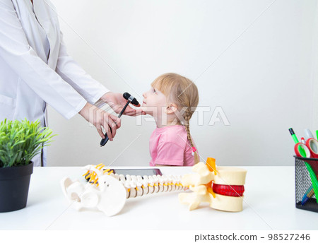 A neurologist examines the child and checks the mandibular reflex with a neurological hammer. Copy space for text A neurologist examines the child and checks the mandibular reflex with a neurological hammer. Copy space for text 98527246