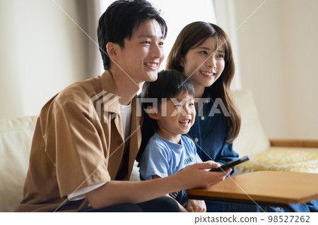 A smiling Japanese family sitting on the sofa / Child-rearing family image A smiling Japanese family sitting on the sofa / Child-rearing family image 98527262
