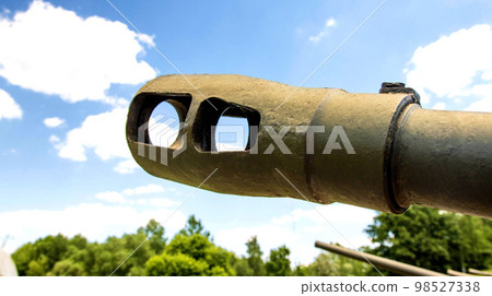 The muzzle of a cannon of a military tank against the blue sky, close-up. The concept of military conflict, aggression. The muzzle of a cannon of a military tank against the blue sky, close-up. The concept of military conflict, aggression. 98527338