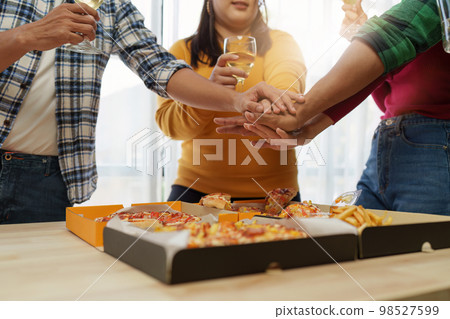 Friends at birthday party clinking glasses with champagne and pizza, enjoying Christmas vacation, pizza on the table. Holiday Party event. Friends at birthday party clinking glasses with champagne and pizza, enjoying Christmas vacation, pizza on the table. Holiday Party event. 98527599