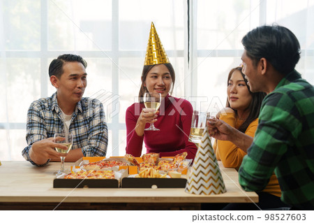 Friends at birthday party clinking glasses with champagne and pizza, enjoying Christmas vacation, pizza on the table. Holiday Party event. Friends at birthday party clinking glasses with champagne and pizza, enjoying Christmas vacation, pizza on the table. Holiday Party event. 98527603