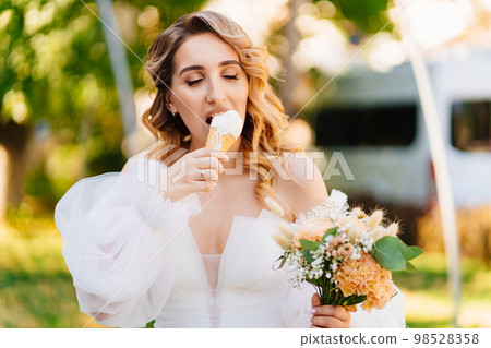 the bride eats an ice cream cone in the park the bride eats an ice cream cone in the park 98528358