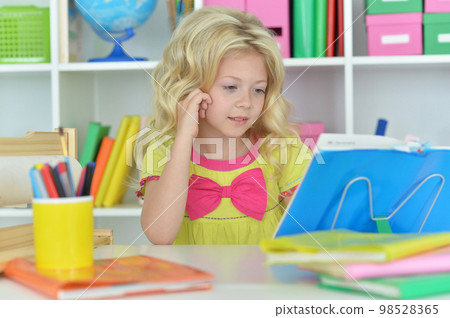 little girl studying at home at the table 98528365