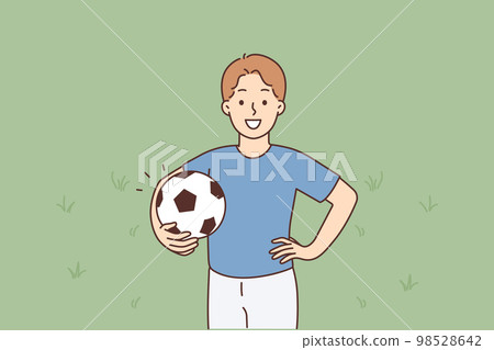 A young smiling boy stands holding a soccer ball 98528642
