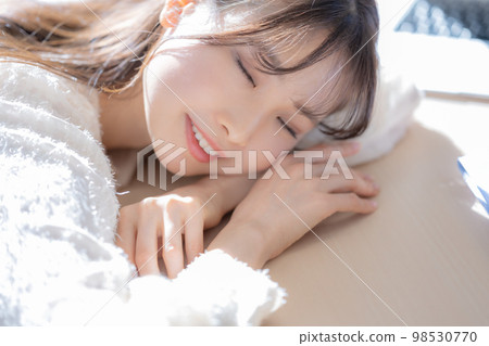 A young woman lying down on a desk and closing her eyes A young woman lying down on a desk and closing her eyes 98530770