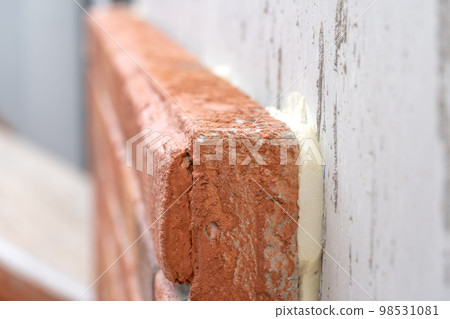 Closeup to the foam brick installation by foam glue stick on cement wall at outdoor field 98531081