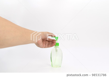 Asian mand hand holds a gel alcohol pump bottle and ready to pushes on it. It's an isolated object on the white clear screen in studio light. 98531786