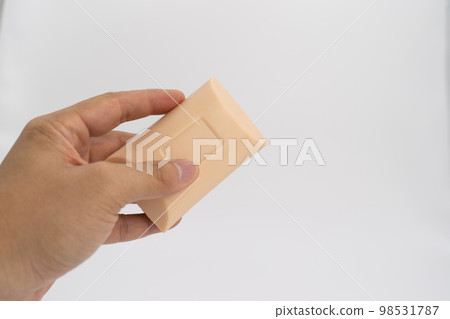 Asian mand hand holds rectangle cream color soap in studio light on white clear background. 98531787