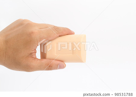 Asian mand hand holds rectangle cream color soap in studio light on white clear background. 98531788