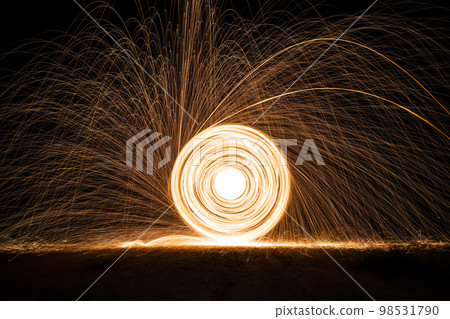 Spinning and burning Steel wool sparkle fire in the circle shape with long speed shutter shoot glowing light line to the ground. 98531790