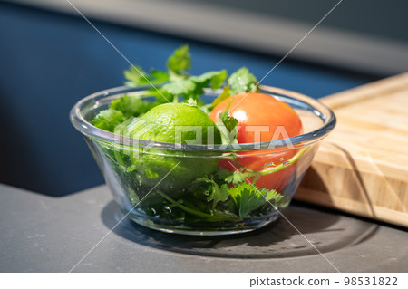 close up fresh green lime and tomato in glass bowl in studio light at kitchen. close up fresh green lime and tomato in glass bowl in studio light at kitchen. 98531822