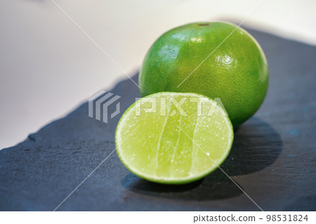 close up fresh lime, lemone in studio light on black stone plate in the kitchen. close up fresh lime, lemone in studio light on black stone plate in the kitchen. 98531824