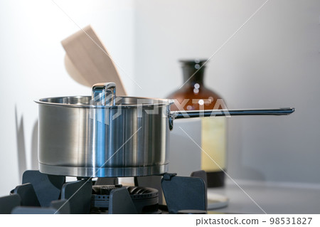 stainless steel pot on electronic modern flat stove in low light on counter kitchen room stainless steel pot on electronic modern flat stove in low light on counter kitchen room 98531827