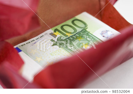 Gift bundle of one hundred euro banknotes wrapped in red paper. Business bonus. Cash prize for birthday 98532004