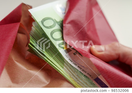 Bonus in one hundred euro banknotes wrapped in red gift paper in hands. Fortune and Wealth concept Bonus in one hundred euro banknotes wrapped in red gift paper in hands. Fortune and Wealth concept 98532006