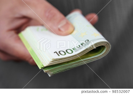 A person giving a bundle of one hundred Euro banknotes in closeup 98532007