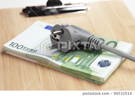 Electric plug on a pile of European euro banknotes. The concept of efficient electricity consumption at a high price. Saving home budget money idea Electric plug on a pile of European euro banknotes. The concept of efficient electricity consumption at a high price. Saving home budget money idea 98532018
