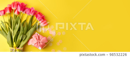 Top view of pink tulips bouquet, wrapped with yellow ribbon and gift box overbright yellow background. Copy space. Happy Easter, 8 march, Woman day, Saint Valentine, Birthday, Mom day concept 98532226