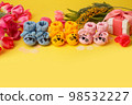 Pregnancy motherhood perenthood concept, Three colorful pairs of baby booties, gift box, tulips on yellow background, baby shower, first birthday party banner, handmade socks, mother mom 98532227