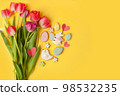 Happy Easter. Multi-colored pastel easter cookies gingerbread, seasonal flowers tulips on yellow background. Easter concept, copy space, flyer, banner, coupon, greeting card, invitation 98532235