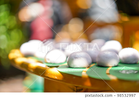 mini purple sweet steaming bun on decorative palm leaf on wood plate in outdoor field. 98532997