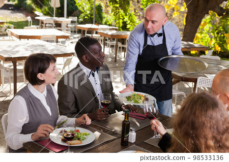 Good friends drink red wine in a summer cafe Good friends drink red wine in a summer cafe 98533136