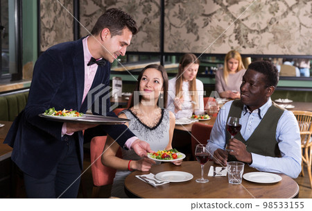 Waiter serving couple in restaurant Waiter serving couple in restaurant 98533155