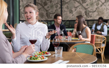 Cheerful woman with female friend in restaurant Cheerful woman with female friend in restaurant 98533156