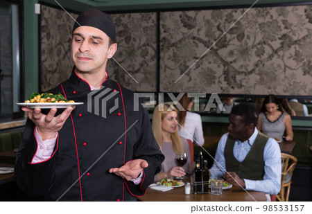 Professional chef inviting to degustation of dish Professional chef inviting to degustation of dish 98533157