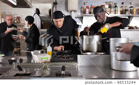 Chef with team preparing food in kitchen of restaurant Chef with team preparing food in kitchen of restaurant 98533244