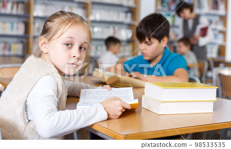 Tween girl in school library Tween girl in school library 98533535