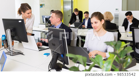Coworkers engaged in open plan office Coworkers engaged in open plan office 98533542
