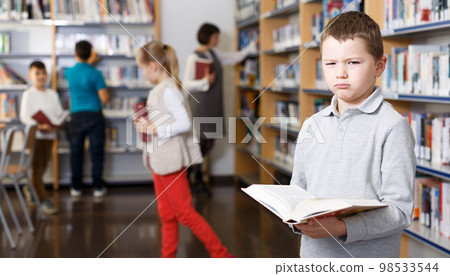 Upset tween boy browsing book Upset tween boy browsing book 98533544