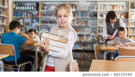 Smiling teen girl with pile of books Smiling teen girl with pile of books 98533549