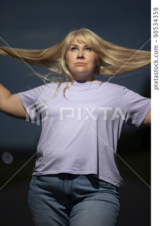 Plump middle aged woman posing in jeans on the street, overweight xxl. A full girl enjoys life. 98534359