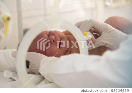 A newborn baby lies in boxes in the hospital. A child in an incubator. Neonatal and Premature Intensive Care Unit A newborn baby lies in boxes in the hospital. A child in an incubator. Neonatal and Premature Intensive Care Unit 98534459