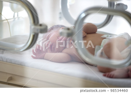 A newborn baby lies in boxes in the hospital. A child in an incubator. Neonatal and Premature Intensive Care Unit A newborn baby lies in boxes in the hospital. A child in an incubator. Neonatal and Premature Intensive Care Unit 98534460