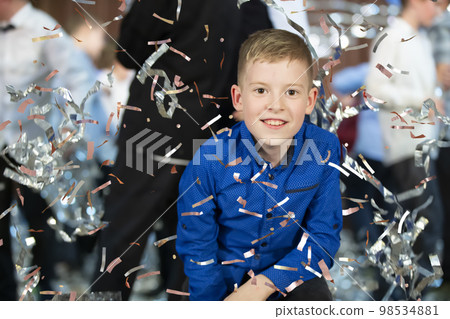Happy little boy in confetti.Magic time - Portrait of a very happy child with hands smiling while falling confetti. At a children's party. Happy little boy in confetti.Magic time - Portrait of a very happy child with hands smiling while falling confetti. At a children's party. 98534881