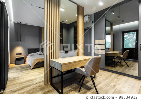 Modern luxury bedroom in loft style with dark and grey style. Dark headboard and wooden floor with wall panel 98534912