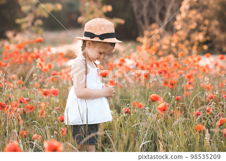 Cute funny baby girl 2-3 year old wear straw hat and white summer dress over flower meadow background. Kid laughing outdoors over nature Cute funny baby girl 2-3 year old wear straw hat and white summer dress over flower meadow background. Kid laughing outdoors over nature 98535209