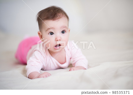 Cute baby under 1 year old wearing pajamas crawling in bed at home close up. Childhood. Good morning. Healthy lifestyle. 98535371