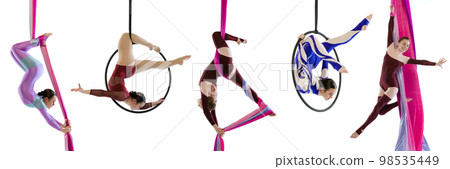 Young flexible girls, professional air gymnasts, fly yoga athletes training on hoop and ribbons isolated on white background. Concept of sport, action, lifestyle, beauty, hobby. Young flexible girls, professional air gymnasts, fly yoga athletes training on hoop and ribbons isolated on white background. Concept of sport, action, lifestyle, beauty, hobby. 98535449
