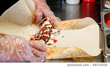 Chef cooking lula kebab in turkish restaurant. Cook rolling kebab and minced meat wrapping in pita lavash close up Chef cooking lula kebab in turkish restaurant. Cook rolling kebab and minced meat wrapping in pita lavash close up 98535626