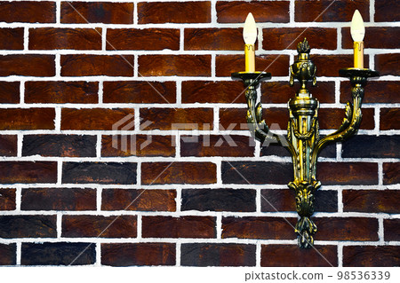 Double gold candlestick lamp on red black brick wall Double gold candlestick lamp on red black brick wall 98536339